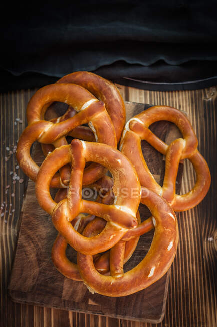 Stack of freshly baked pretzels on a wooden chopping board — Stock Photo