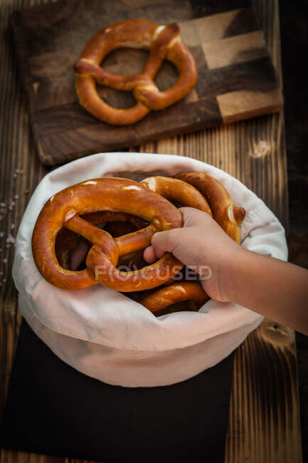 Hand reaching for a freshly baked pretzel — Stock Photo