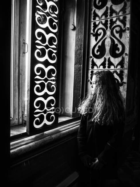 Portrait d'une fille regardant par la fenêtre — Photo de stock