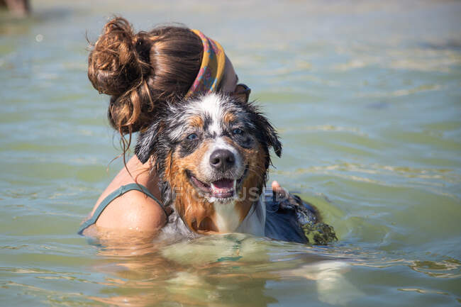 Mulher nadando no oceano com um cão pastor australiano, Flórida, EUA — Fotografia de Stock