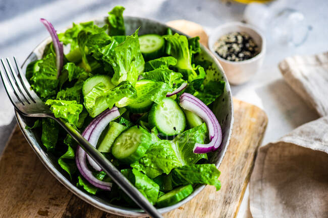 Conceito de salada verde saudável com folhas de salada de iceberg, pepino, óleo de gergelim e sementes servidas em uma tigela — Fotografia de Stock