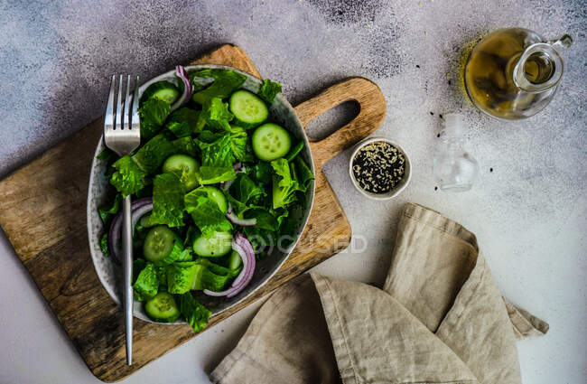 Concepto saludable de ensalada verde con hojas de ensalada de iceberg, pepino, aceite de sésamo y semillas servidas en un tazón - foto de stock