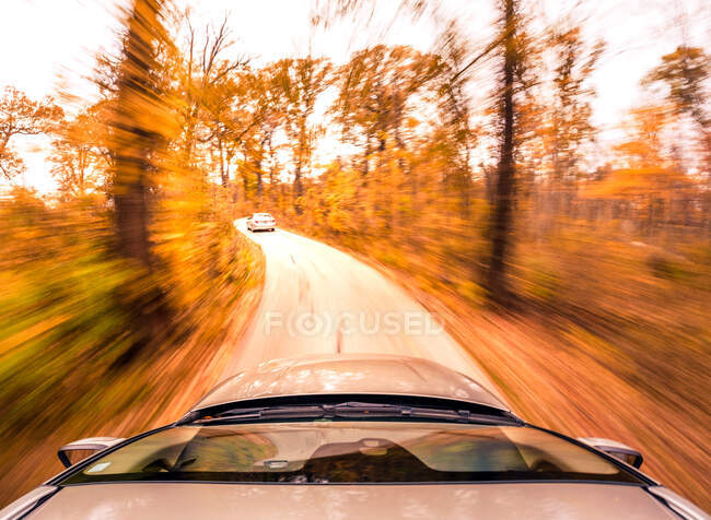 Acelerando carro dirigindo ao longo de uma estrada de outono, EUA — Fotografia de Stock