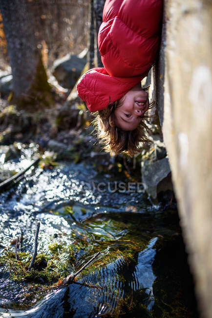 Boy hanging upside down over the edge of a bridge, сша — стоковое фото