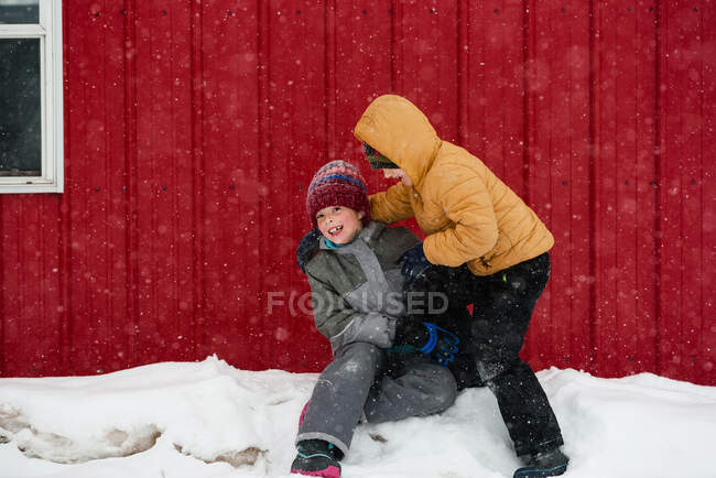 Two children playing in the snow outside a house, USA — Stock Photo