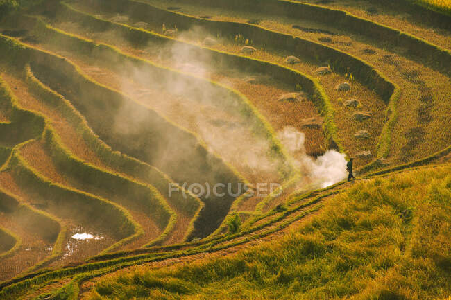 Farmer walking past a bonfire in Tiered rice terraces, Mu Cang Chai, Vietnam — Stock Photo