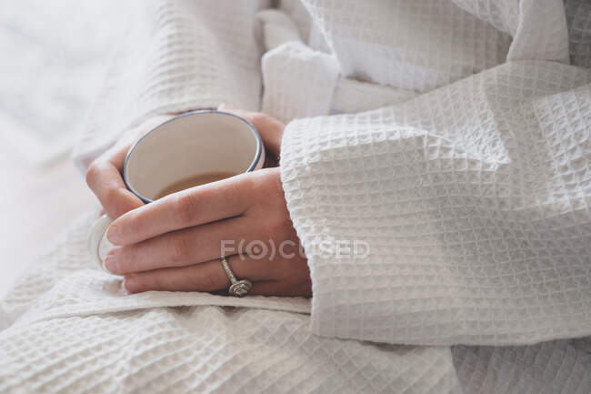 Mujer en bata disfrutando de una taza de té - foto de stock