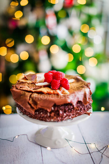 Chocolate cake on a table in front of a Christmas tree — Stock Photo