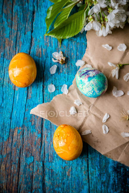 Multi coloured Easter Eggs on brown paper with flower petals — Stock Photo