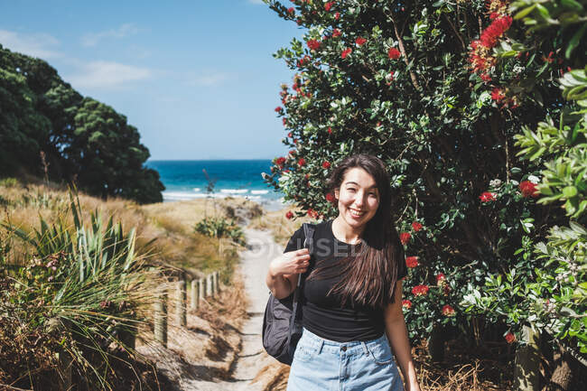 Lächelnde Frau auf dem Fußweg zum Strand, Mangawhai Heads, Northland, Nordinsel, Neuseeland — Stockfoto