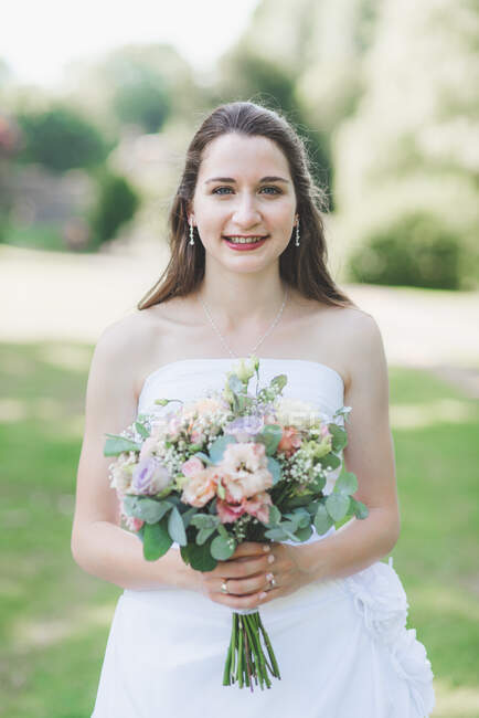Retrato de una novia sonriente sosteniendo un ramo de bodas - foto de stock