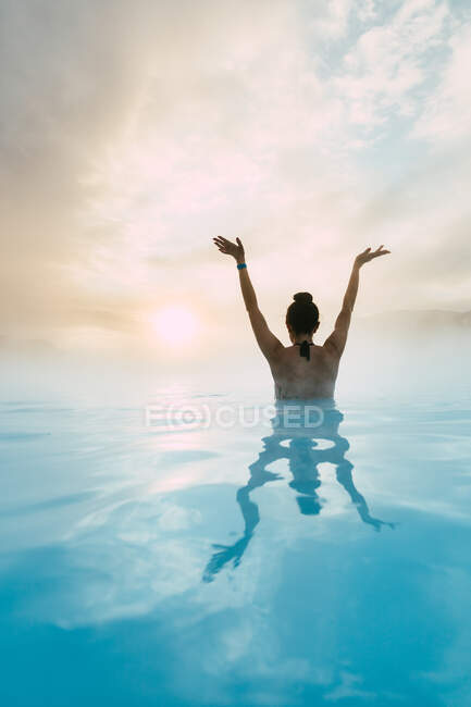 Mujer de pie en la Laguna Azul con los brazos en el aire, Islandia - foto de stock