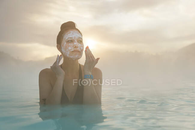 Mulher de pé na Lagoa Azul colocando lama em seu rosto, Islândia — Fotografia de Stock