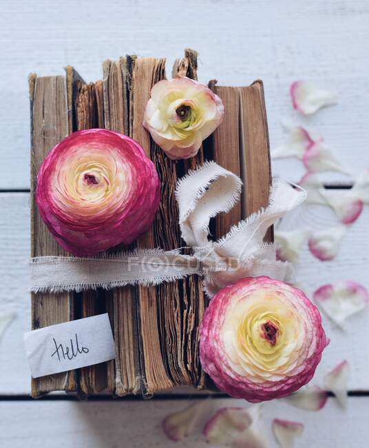 Stack of old books with flowers on a wooden table — Stock Photo