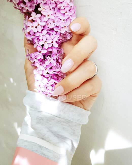 Close-up de uma mulher segurando uma flor lilás — Fotografia de Stock