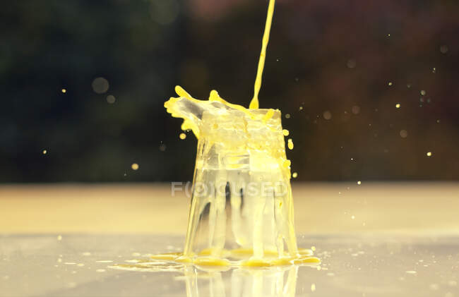 Orange juice pouring onto an upside down glass - foto de stock