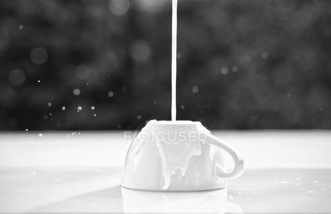 Milk pouring onto an upside down cup - foto de stock