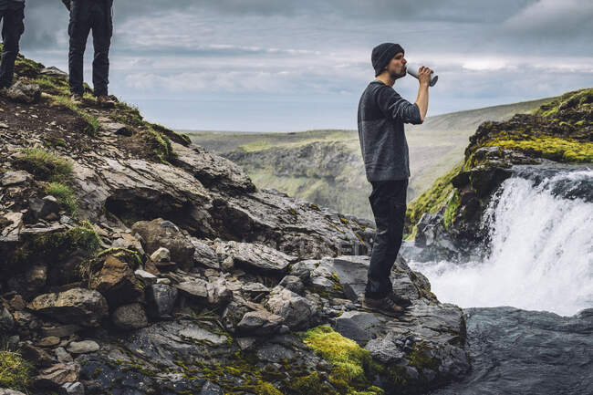 Hombre bebiendo agua dulce de un río cerca de Landmannalaugar, Reserva Natural de Fjallabak, Islandia Central del Sur, Islandia - foto de stock