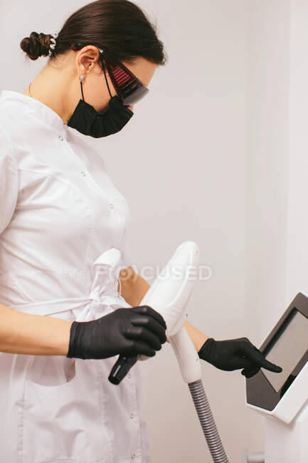 Esteticista en una clínica de belleza de pie junto a una máquina de pelado de carbono - foto de stock