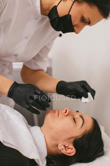 Esteticista limpieza de la cara de una mujer después de un tratamiento de belleza de la cáscara de carbono - foto de stock