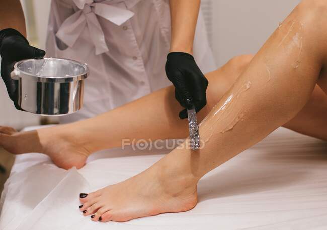 Mujer que tiene gel aplicado para un tratamiento de depilación láser en un salón de belleza - foto de stock