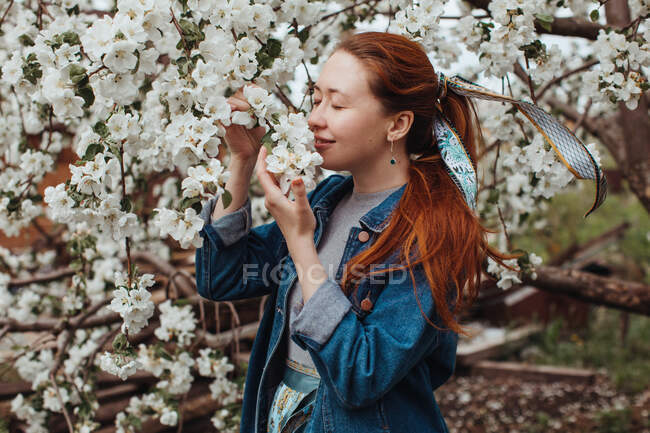 Усміхнена жінка пахне вишневим квітучим деревом — стокове фото