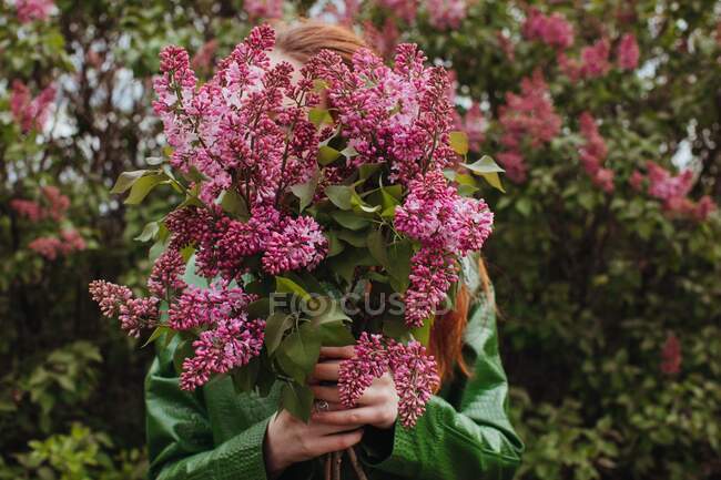 Woman standing outdoors holding freshly picked flowers — Stock Photo