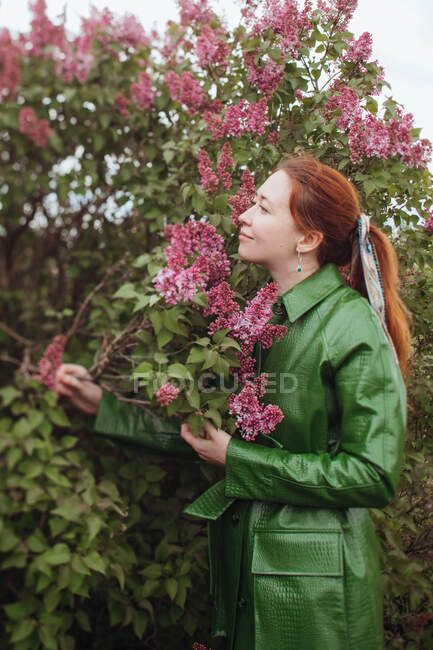 Woman standing outdoors smelling flowers — Stock Photo