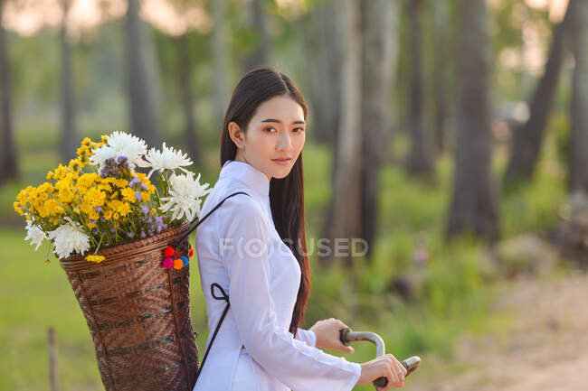 Mulher bonita ciclismo com uma cesta cheia de flores, Tailândia — Fotografia de Stock