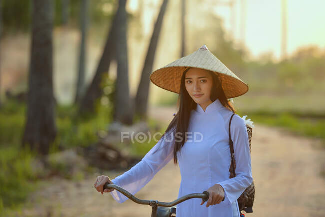 Belle femme portant des vêtements traditionnels debout avec un vélo, Thaïlande — Photo de stock