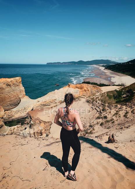 Visão traseira de uma mulher de sportswear em pé no penhasco, Cape Kiwanda Beach, Oregon, EUA — Fotografia de Stock