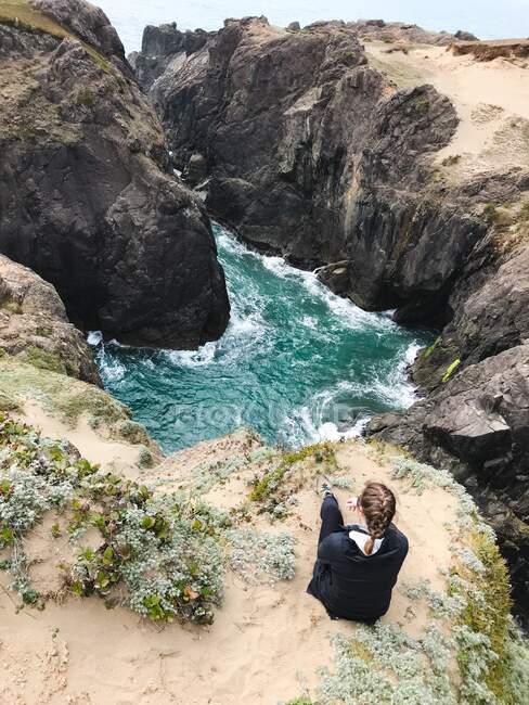 Жінка сидить на прибережних скелях, дивлячись на вид, Samuel H Boardman State Park, Орегон, США — стокове фото