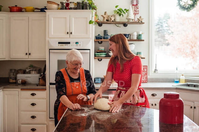 Femme âgée enseignant à sa fille à faire du pain — Photo de stock