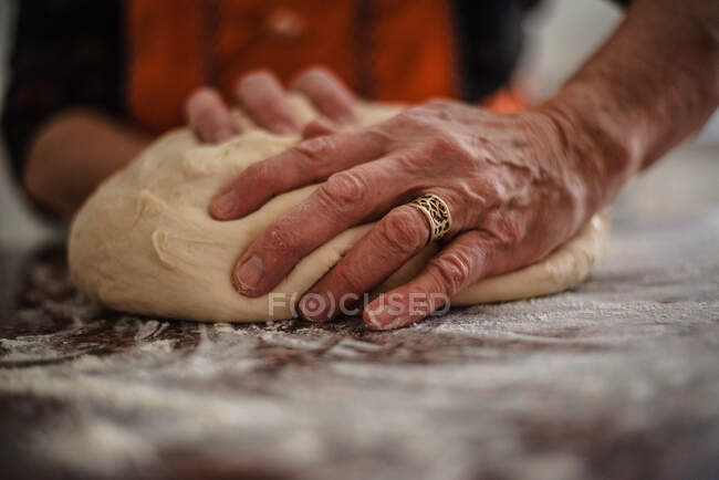 Крупный план рук пожилой женщины, месящих хлеб — стоковое фото
