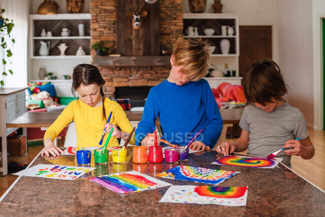 Drei Kinder sitzen in der Küche und malen einen Regenbogen — Stockfoto