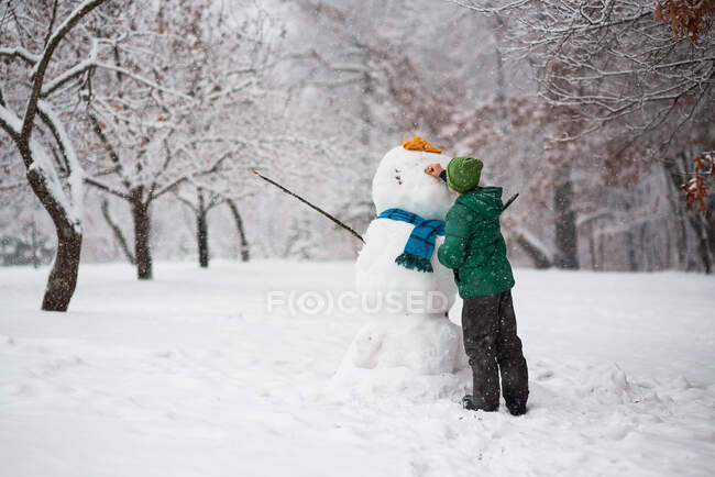 Junge steht im Wald und bastelt einen Schneemann, USA — Stockfoto
