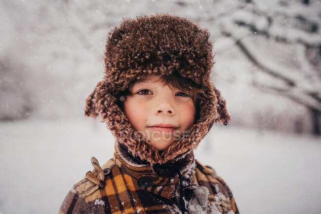 Portrait d'un garçon portant une casquette de chasseur dans la neige, États-Unis — Photo de stock
