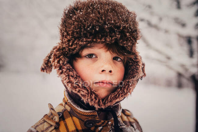 Retrato de un niño con gorra de cazador en la nieve, EE.UU. - foto de stock