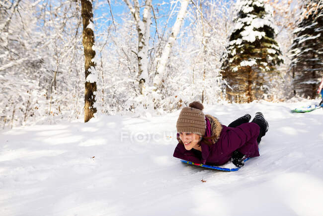 Woman sledding down a hill in the snow, USA — Stock Photo