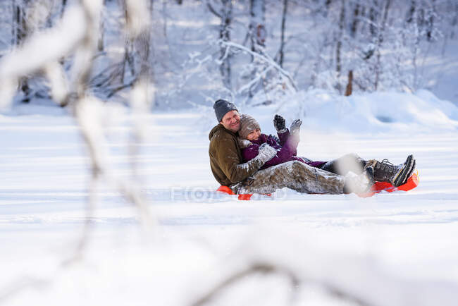 Man and woman sledding down a hill in the snow, USA — Stock Photo