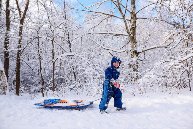Ragazzo che tira una slitta attraverso la neve, USA — Foto stock