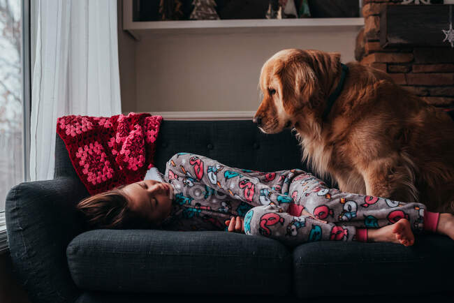 Mädchen liegt mit ihrem Hund auf einem Sofa — Stockfoto