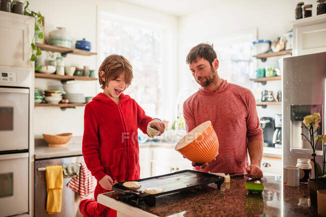 Pai e filho fazendo panquecas pela manhã para o café da manhã — Fotografia de Stock