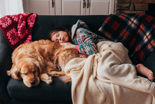 Girl sleeping on a sofa with her dog — Stock Photo