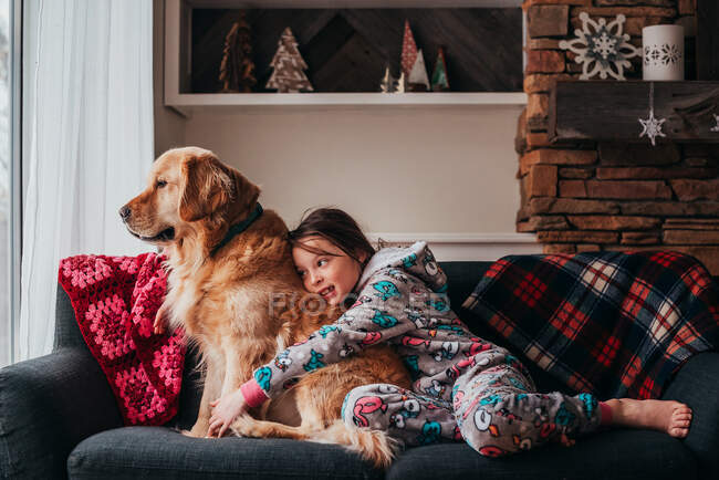 Chica sentada en un sofá con su perro - foto de stock