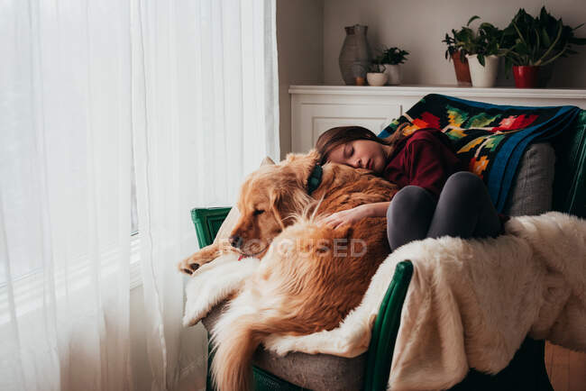 Fille dormir sur un canapé avec son chien — Photo de stock