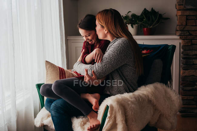 Mãe e filha abraçando em uma poltrona — Fotografia de Stock