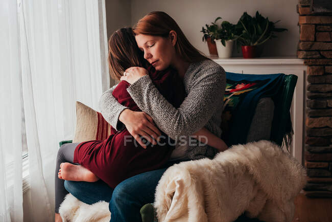 Girl sitting on her mother's lap cuddling — Stock Photo