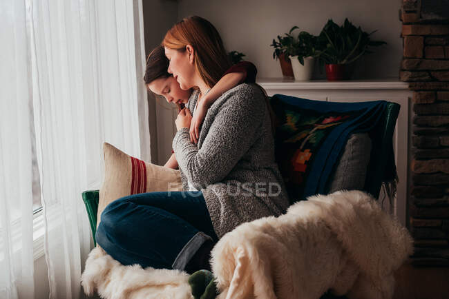 Girl hugging her mother sitting in an armchair — Stock Photo