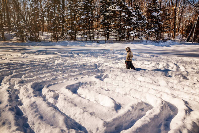 Мальчик идет по снежному лабиринту, США — стоковое фото